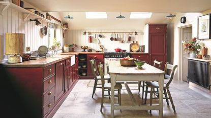 deep red kitchen with white table and chairs, stone floor and cream tongue and groove panelling 