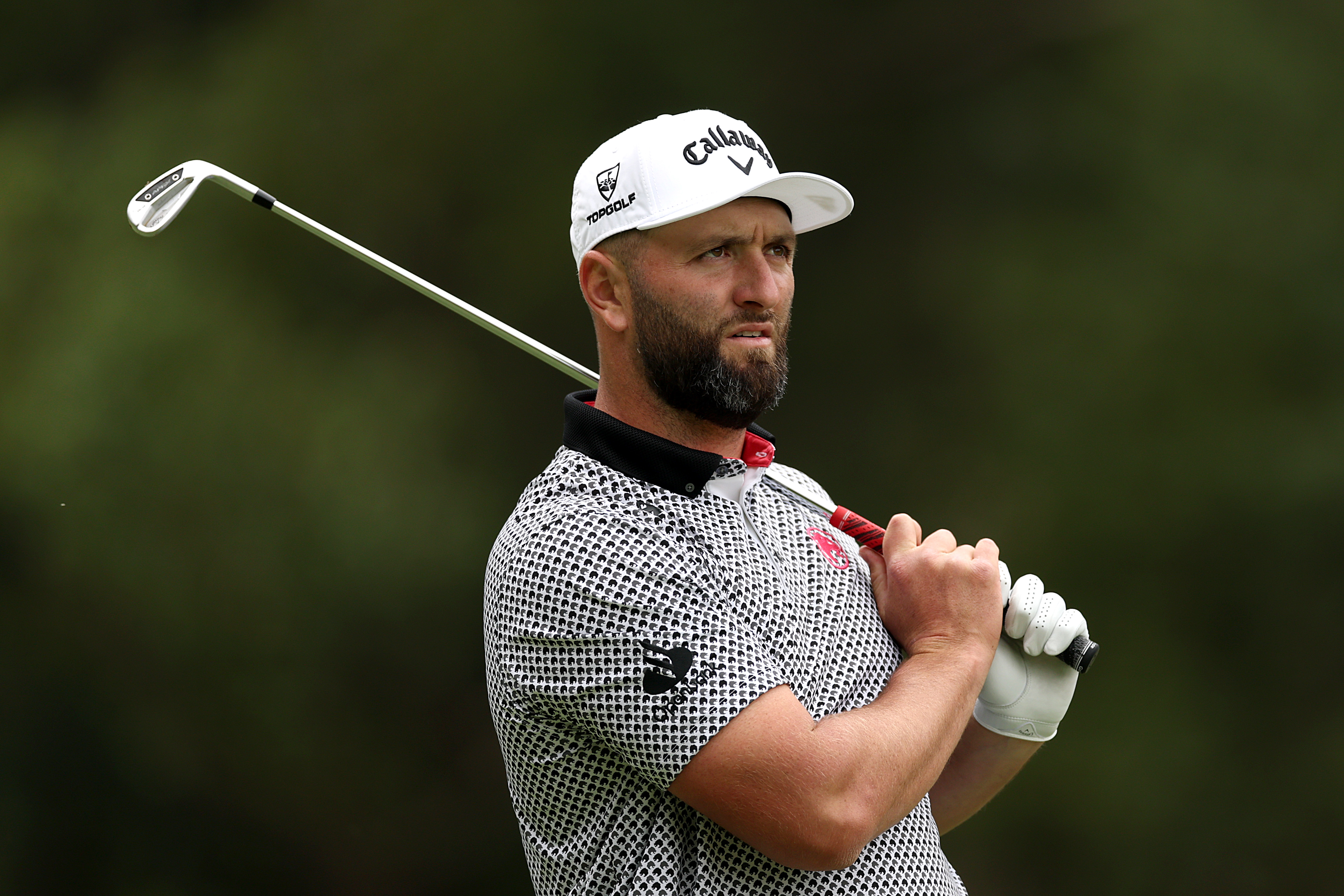 Jon Rahm hits an iron shot and watches it