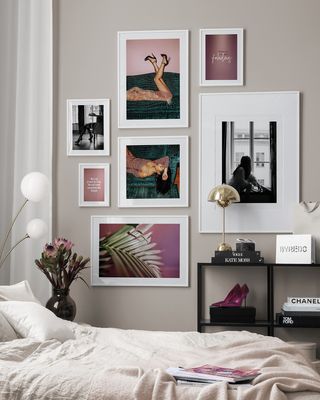 Bedroom photographic gallery wall on light gray painted wall, with mix of purple pink and dark green against light colored linen bedding
