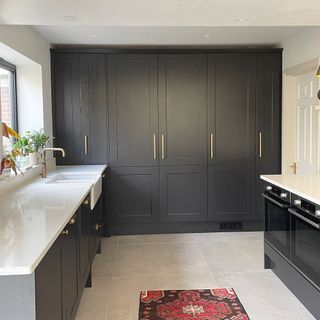 Charcoal grey kitchen with white worktops and wall of full height units