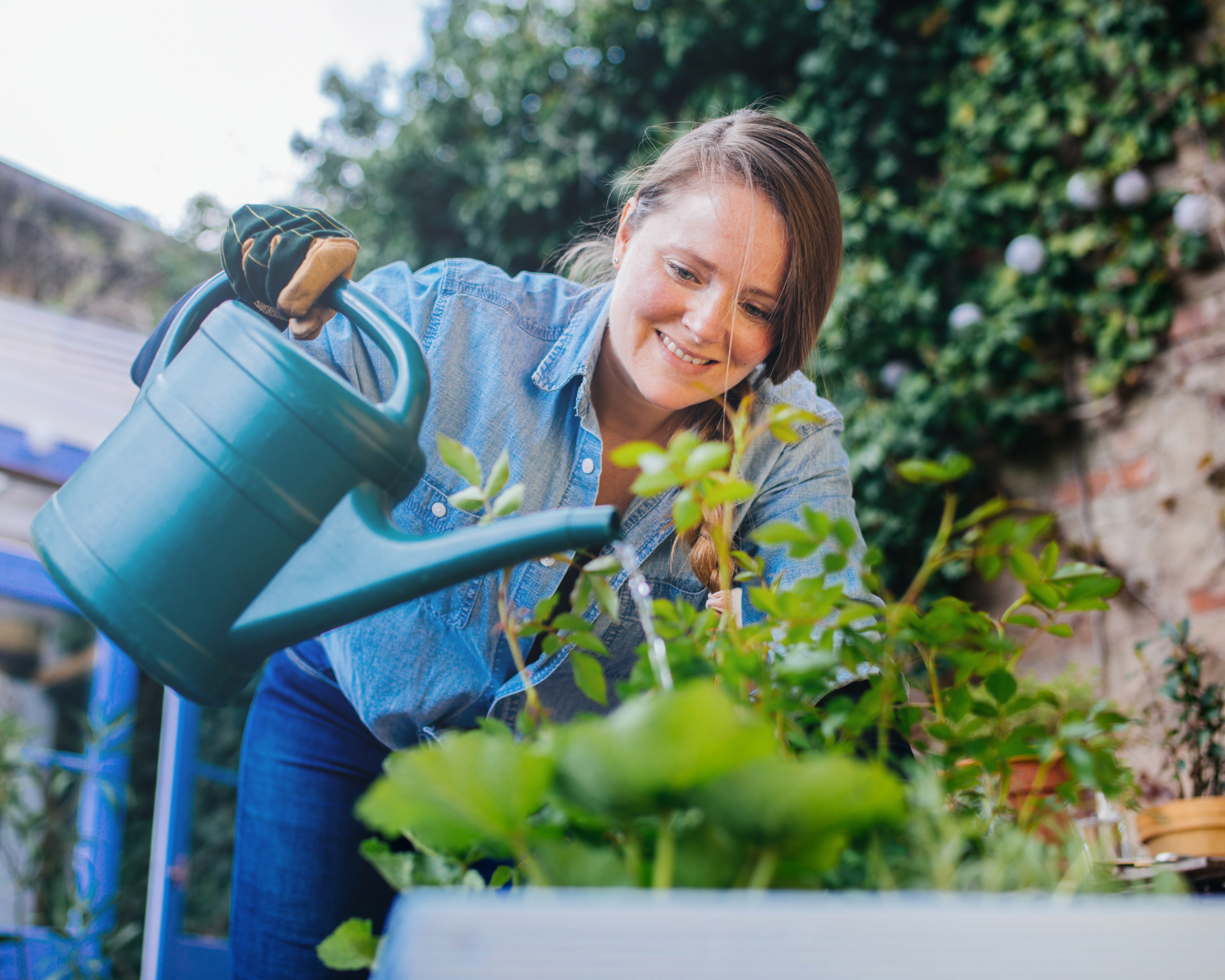 Woman watering flowers in a diy plant pot.