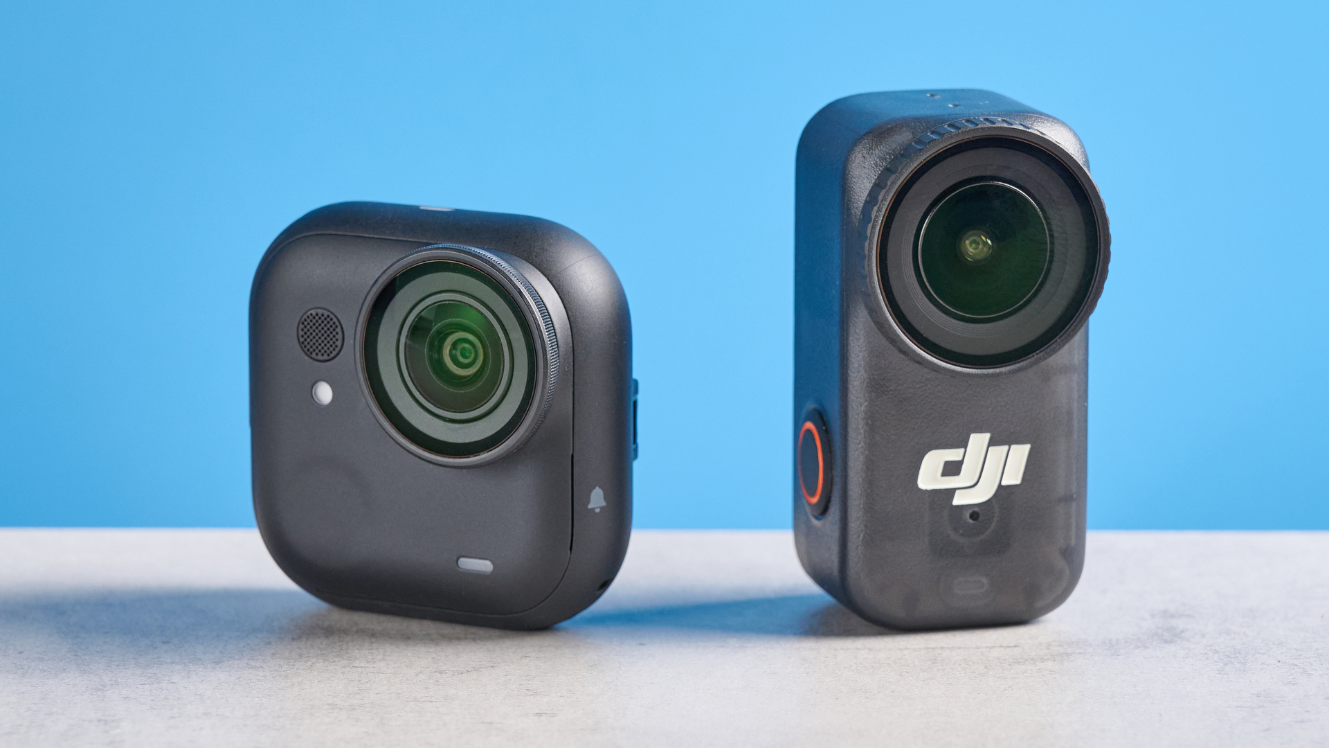 DJI Osmo Nano and Insta360 Go Ultra back to back on a gray surface against a blue background
