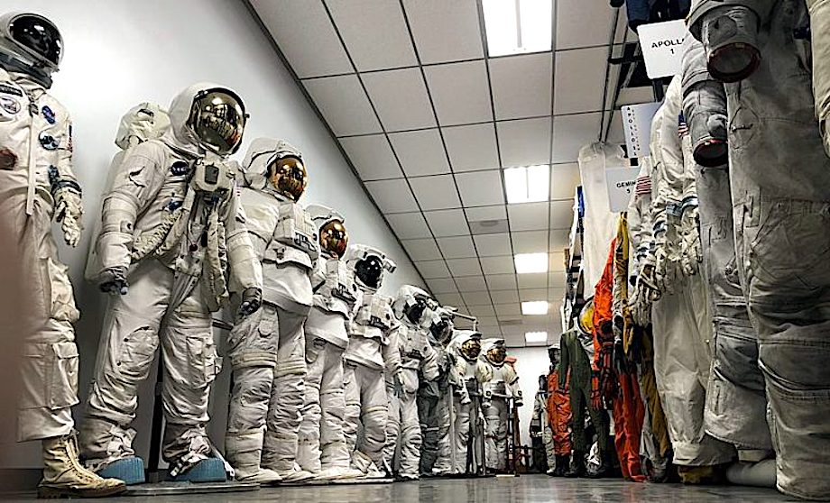Replica spacesuits lined up in a warehouse