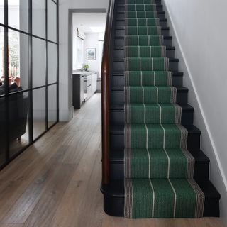 Staircase in hallway with striped runner and Crittall style partition wall