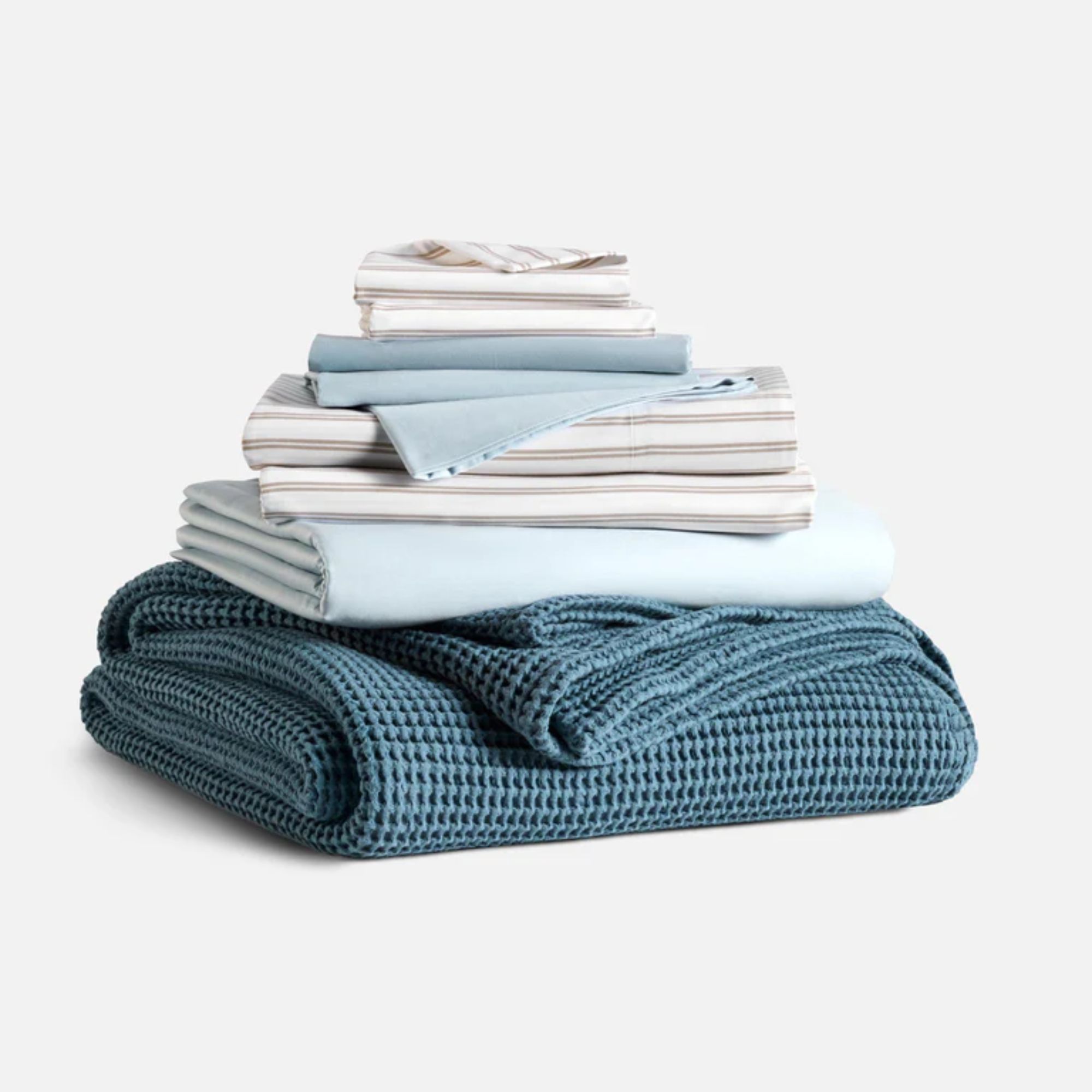 Teal waffle blanket and pale blue sheets with white and taupe striped pillowcases