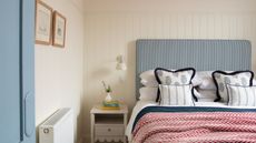 bedroom with white panelled walls, blue striped headboard, red throw on bed