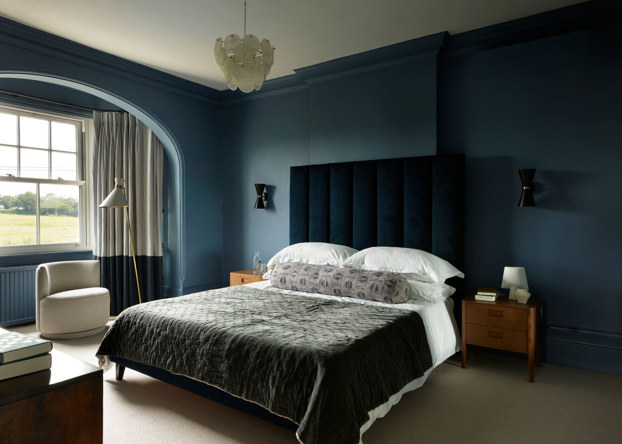 bedroom with dark blue walls, bay window with cream and dark blue curtains