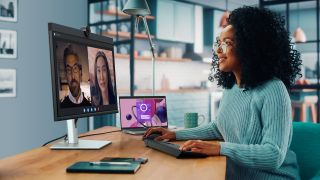 Woman sat at a wooden desk participating in a video conference