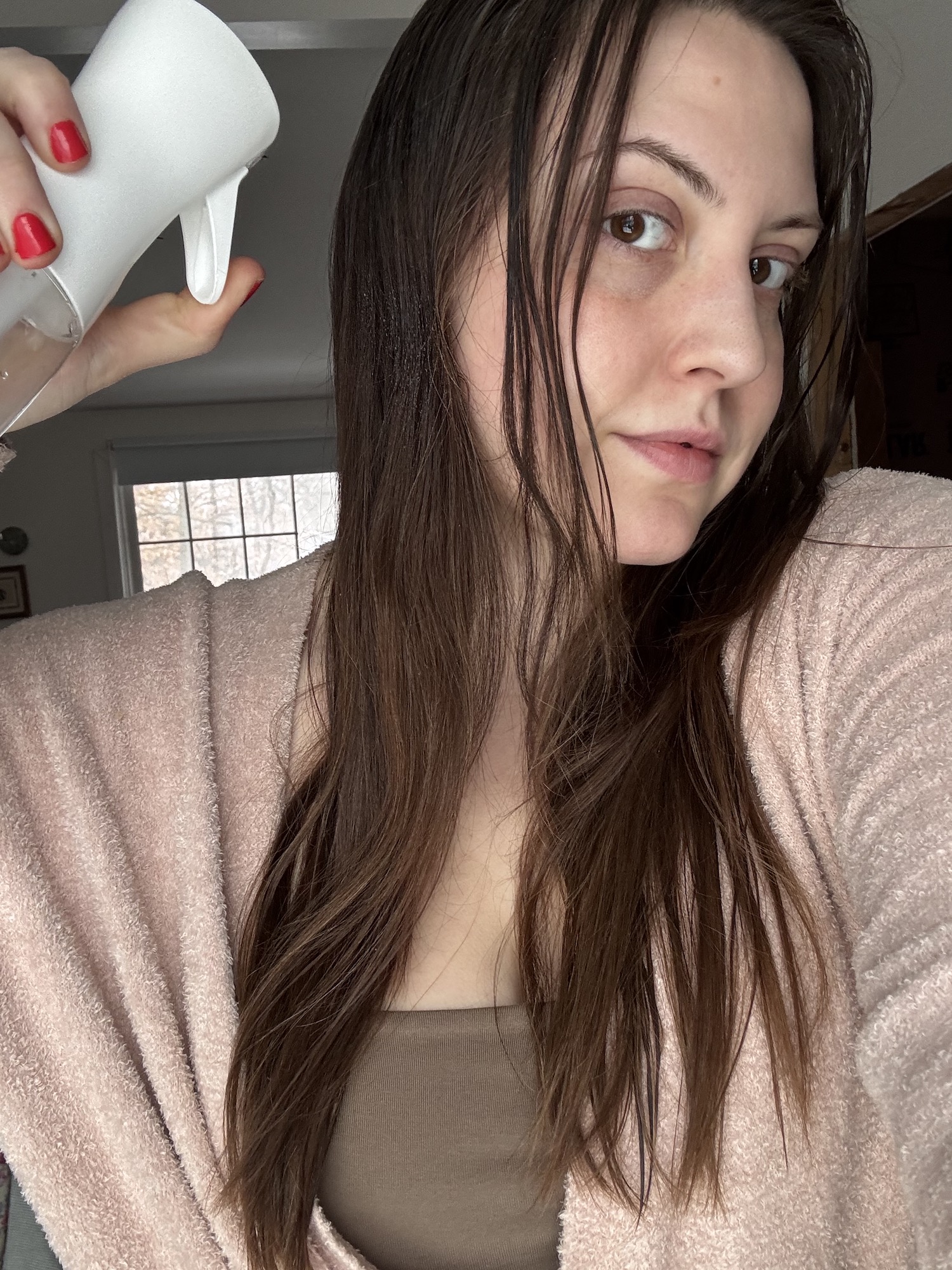 Sophia Vilensky holding her spray bottle during an at-home haircut session.