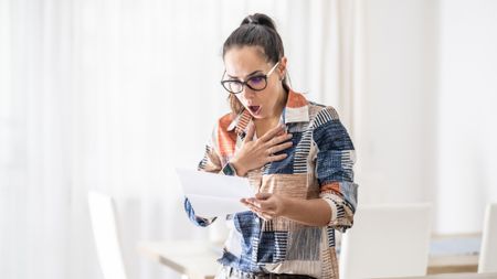 a woman is shocked while reading a letter