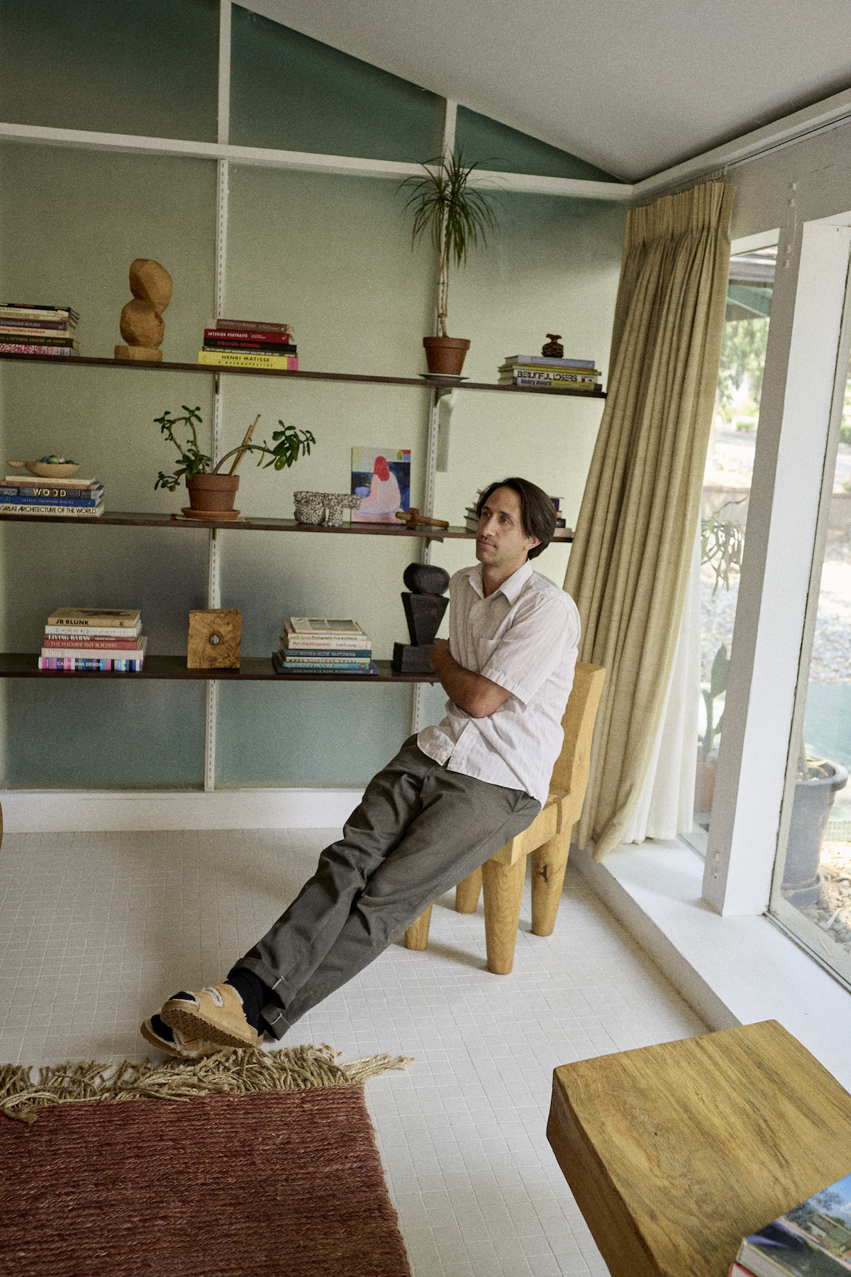 Artist Vince Skelly sits at home with his wooden works in background