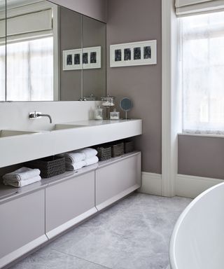 An example of bathroom shelf ideas showing a bathroom with wall-to-wall vanity unit, featuring both open shelves and large drawers