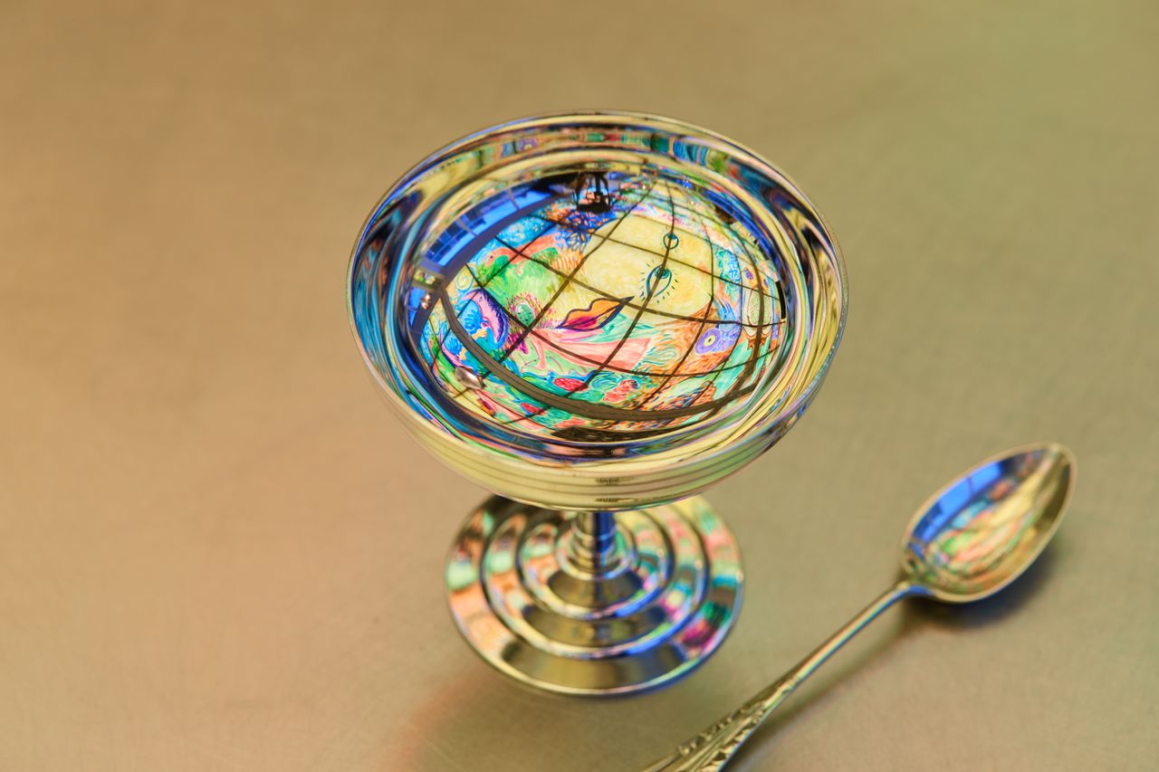 A series of retro-inspired silver ice cream cups and wine glasses are showcased within an ice cream parlor.