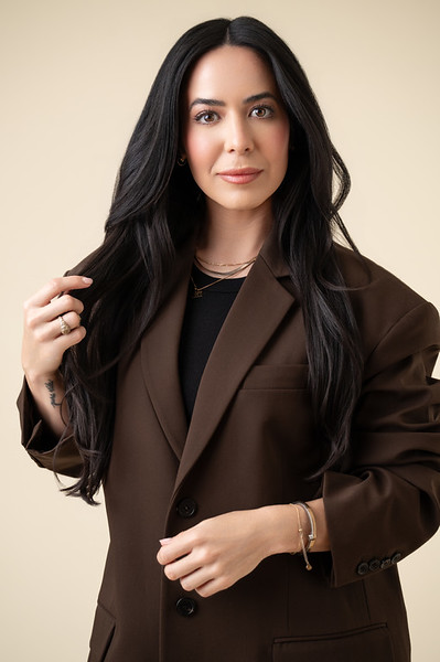 a white woman with long dark hair in a brown blazer