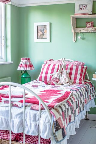 bedroom with green walls and bed with gingham and patchwork