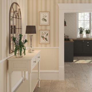 A neutral-coloured hallway with a striped wallpaper on the upper half of the walls and a white console table matching the door frame