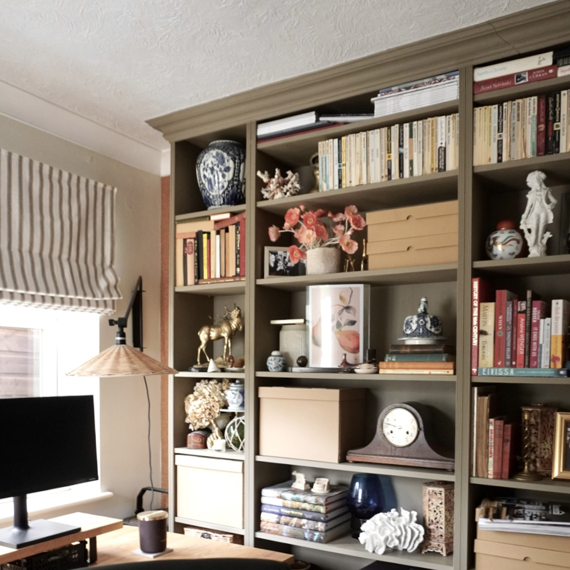 brown bookcase filled with books and ornaments in a home office