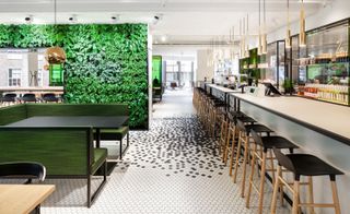 Restaurant partitioned by large green wall of plants