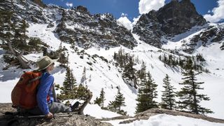 A hiker sitting in a snowy basin in colorado