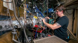 A researcher stood next to high tech physics equipment