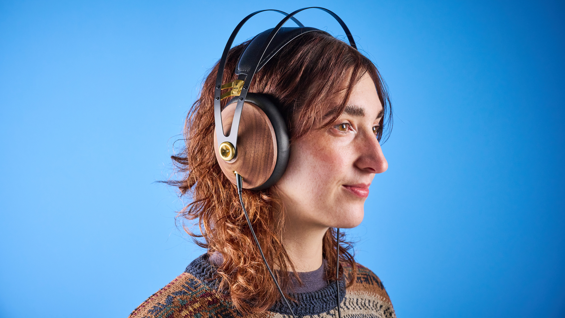 the meze 99 classics 2nd gen headphones with walnut finishes and gold touches against the blue tom&#039;s guide background
