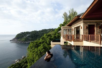 A woman in a luxury hotel pool overlooking Phuket, Thailand.