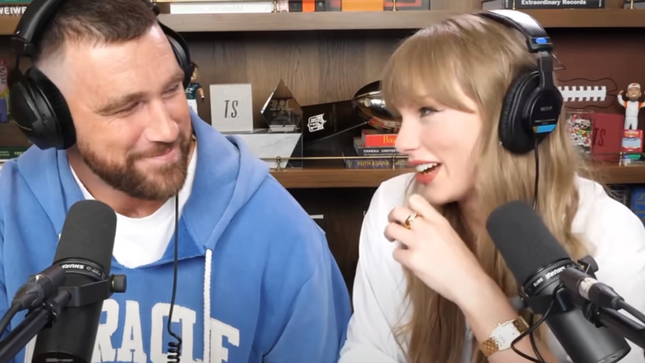 Travis Kelce smiling at Taylor Swift, who's smiling back at him.
