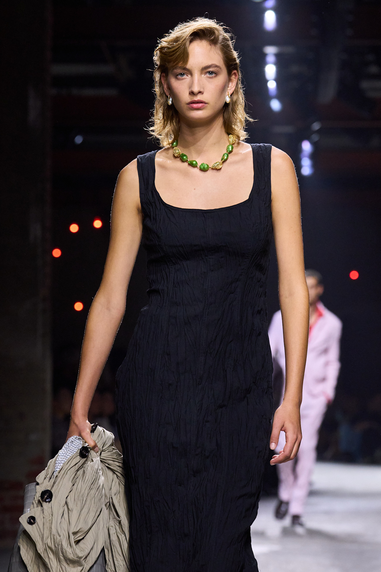 Bottega Veneta runway model wearing a black dress and a green pearl necklace.