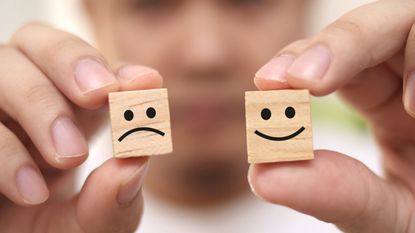 Two wooden blocks have faces drawn on them: One is happy and the other is sad.