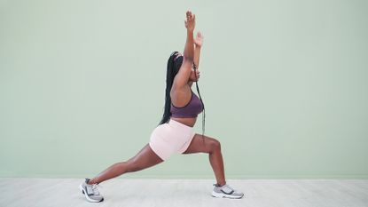 Full body studio shot of a young woman exercising against a green background