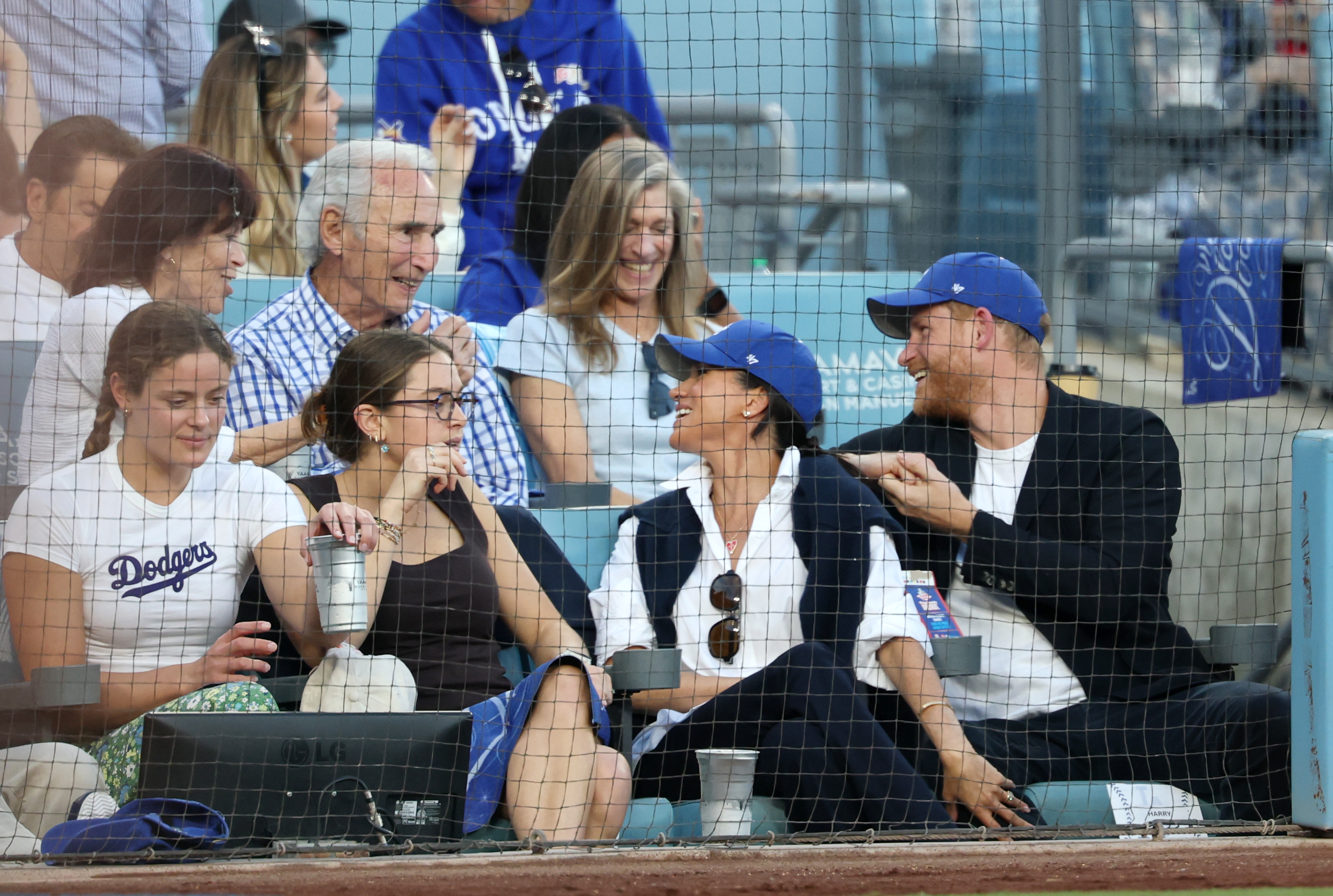 Prince Harry and Meghan Markle turning around to talk to people at Game 4 of the World Series 2025
