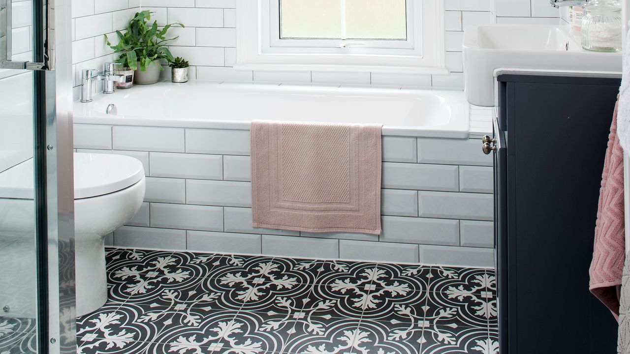 A bathroom with a white tiled bathtub and patterned tiled floor