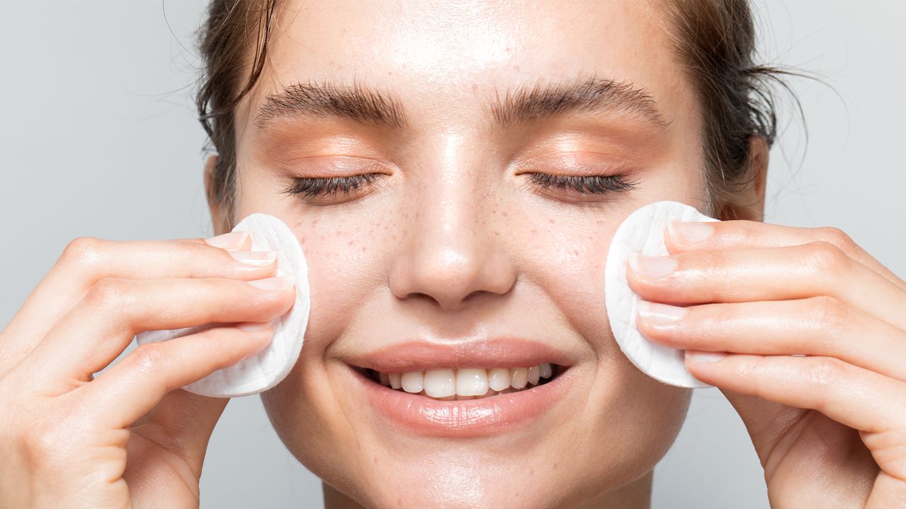 Close up studio shot of a beautiful woman with perfect skin, while she cleaning her face