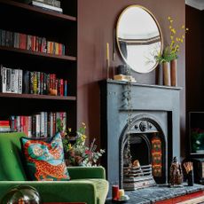 a living room with green velvet armchair, round overmantel mirror and alcove bookshelves