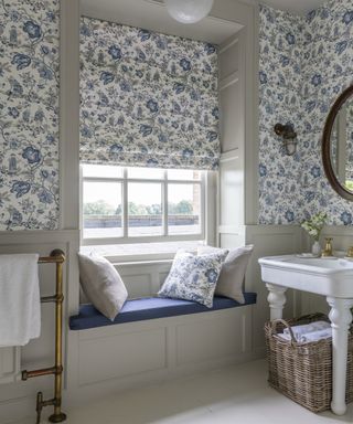 A bathroom with blue and white patterned wallpaper and a window seat