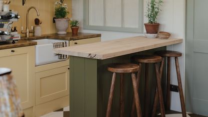 Green and yellow shaker kitchen with peninsula and wooden stools