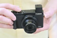 The Canon G5X Mark II being held in two hands with its viewfinder popped open