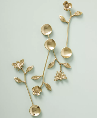 gold teaspoons with thin flower-stem like handles with leaves and bee details