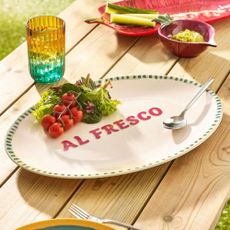 White melamine platter with 'al fresco' written in the middle on a wooden outdoor dining table 