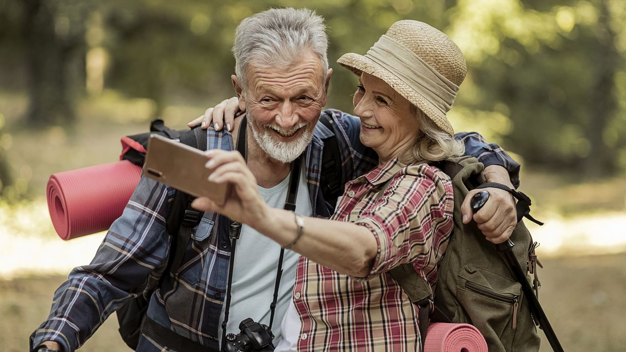 A retired couple out hiking take a selfie together.