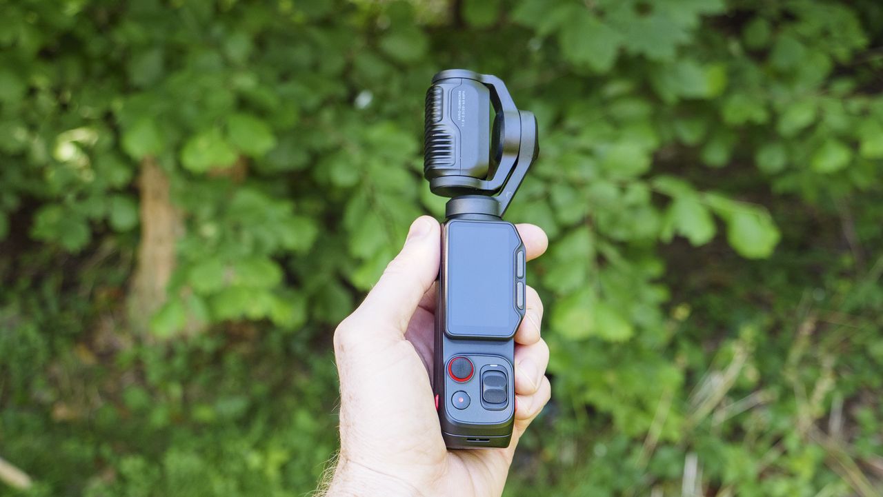 Insta360 Luna Ultra vlogging camera in person's hand, turned off, leafy background