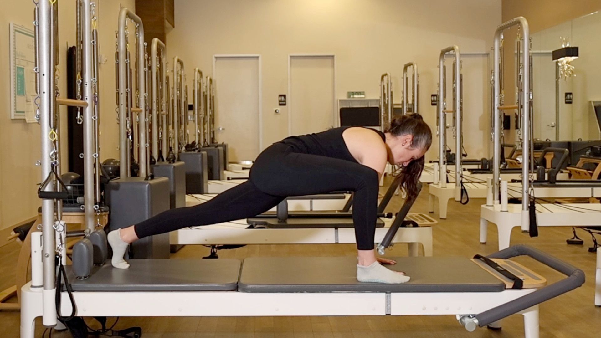 Woman demonstrating a Pilates exercise on the carriage of a Pilates reformer machine