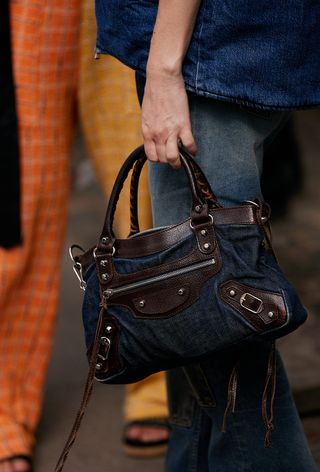 a close street-style photo of a woman carrying one of the most popular vintage bags, Balenciaga city bag in denim styled with an all-denim outfit