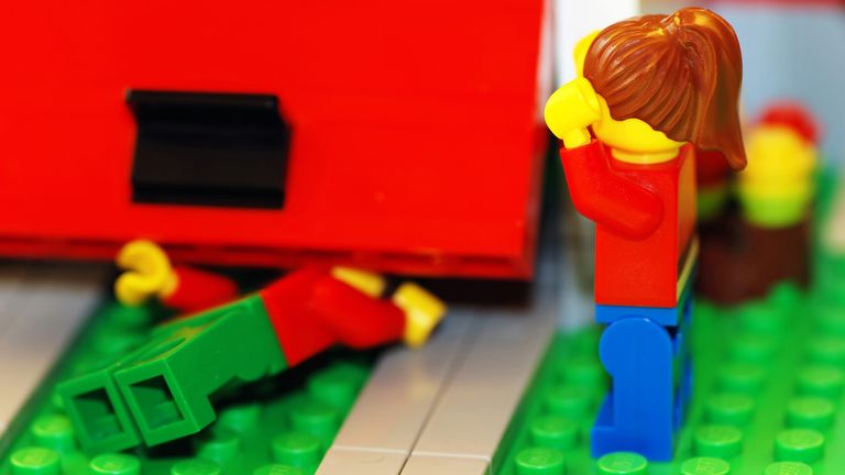 Lego man trapped under building with Lego woman looking shocked with hands in the air