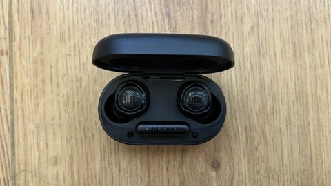 JBL Quantum TWS Air earbuds in charging case on a wooden surface