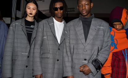 A row of models in grey blazers pose for a picture