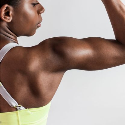 Morning workout routine to build muscle: A woman flexing her arm muscle