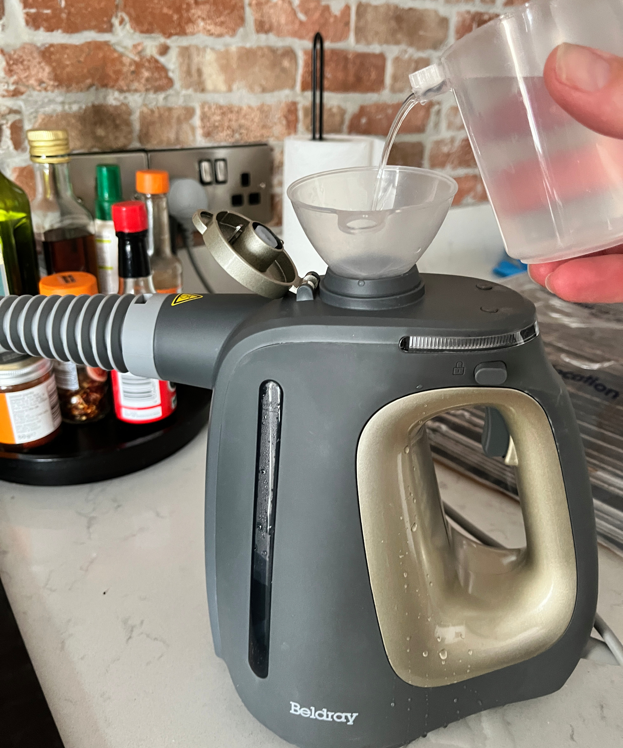 steam cleaner on kitchen worktop being filled with small funnel and water jug