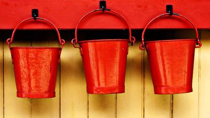 Three red buckets hang on pegs.