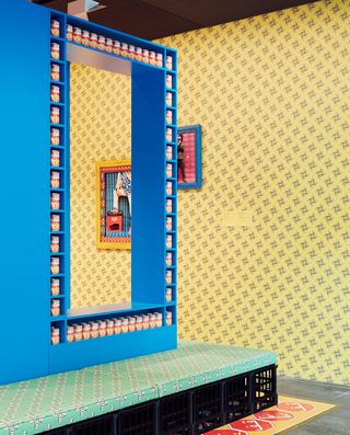 room with green patterned bench, blue shelves and yellow patterned wallpaper